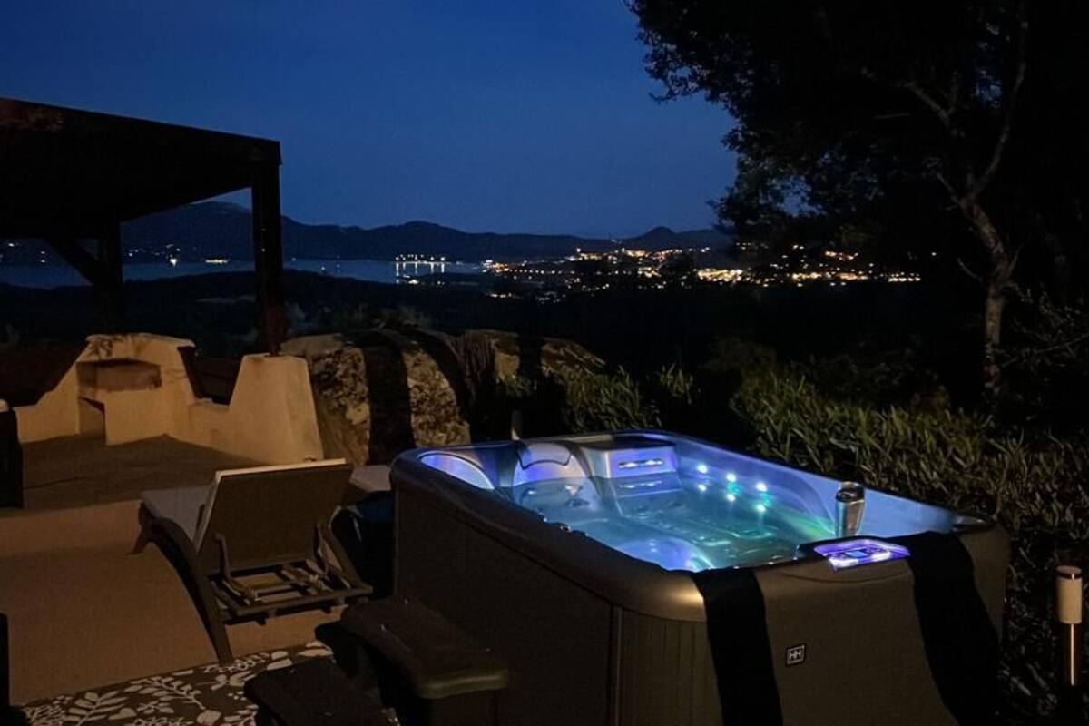Un bain à remous extérieur offrant une vue sur le paysage urbain illuminé la nuit.