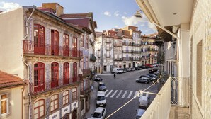 A narrow street with buildings on both sides, a pedestrian crossing, and parked cars. - YOUROPO - ExtendALL (Porto)