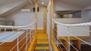 A staircase with a rope barrier, wooden beams, and a ceiling-mounted air conditioner. - YOUROPO - ExtendALL (Porto)