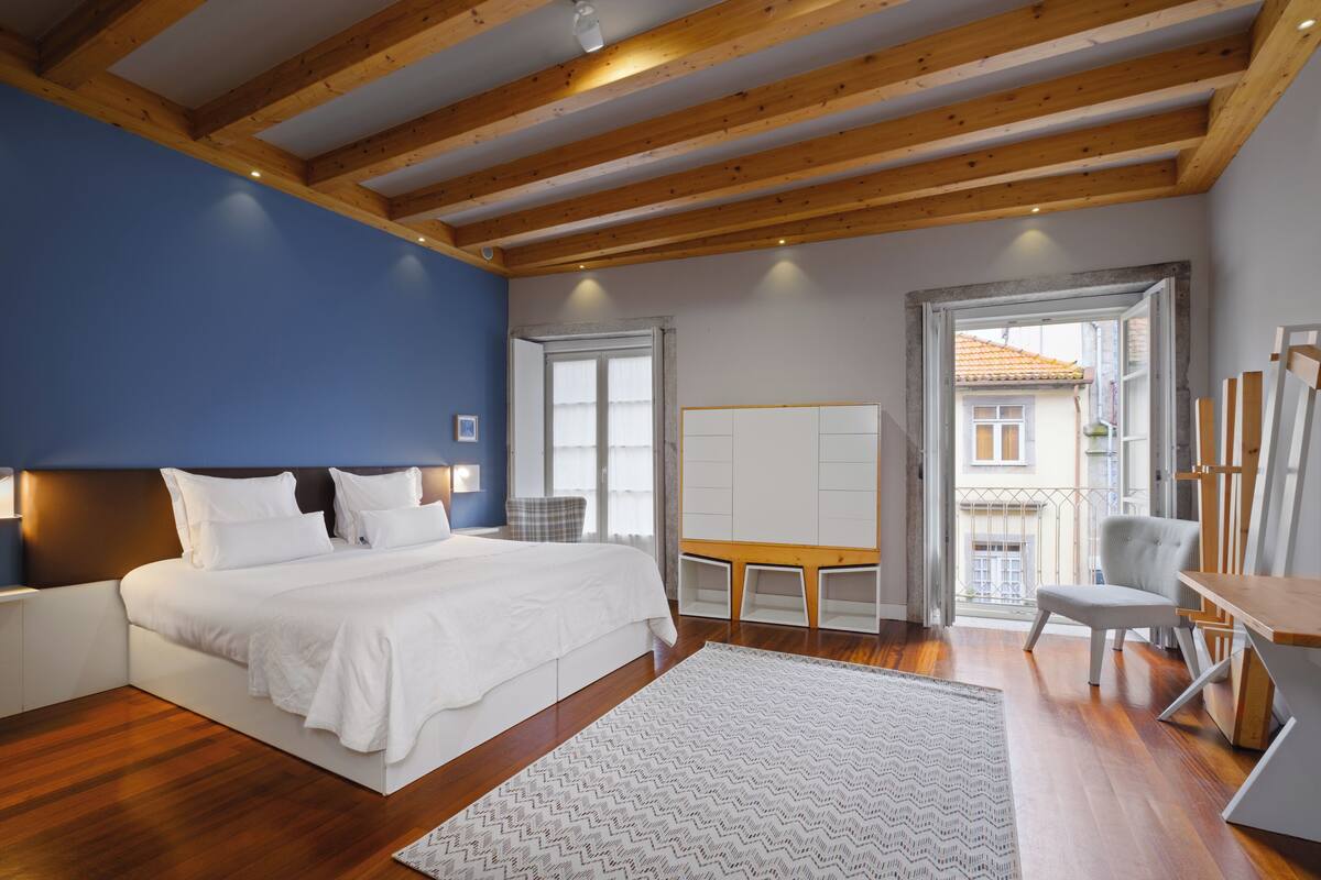 A bedroom with a bed, bedside tables, a desk, and a chair.