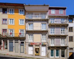 Um edifício com vários andares, varandas, uma loja no térreo e diferentes estilos de janelas.
