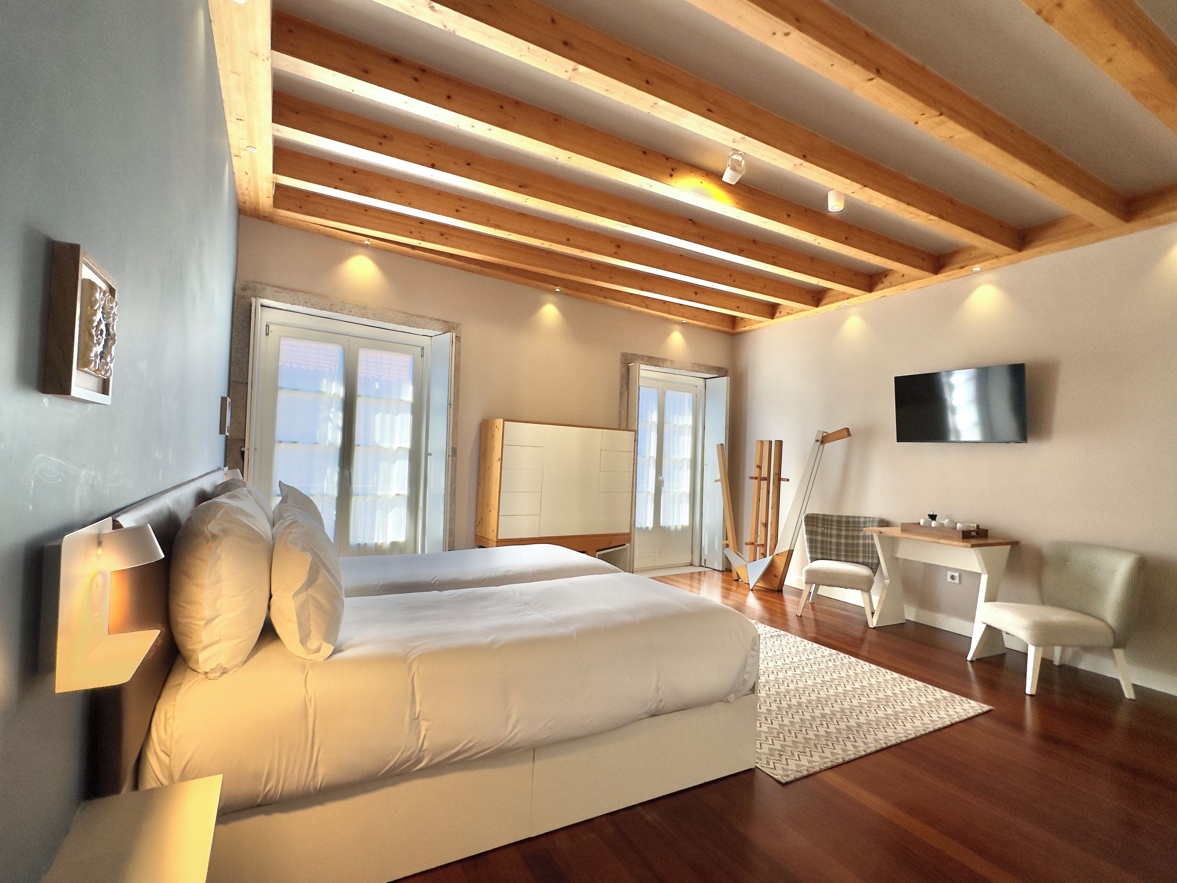 Ett sovrum med en säng, ett skrivbord, en stol, en tv och ett fönster.