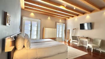 Quarto com cama, escrivaninha, cadeira, televisão e janela.