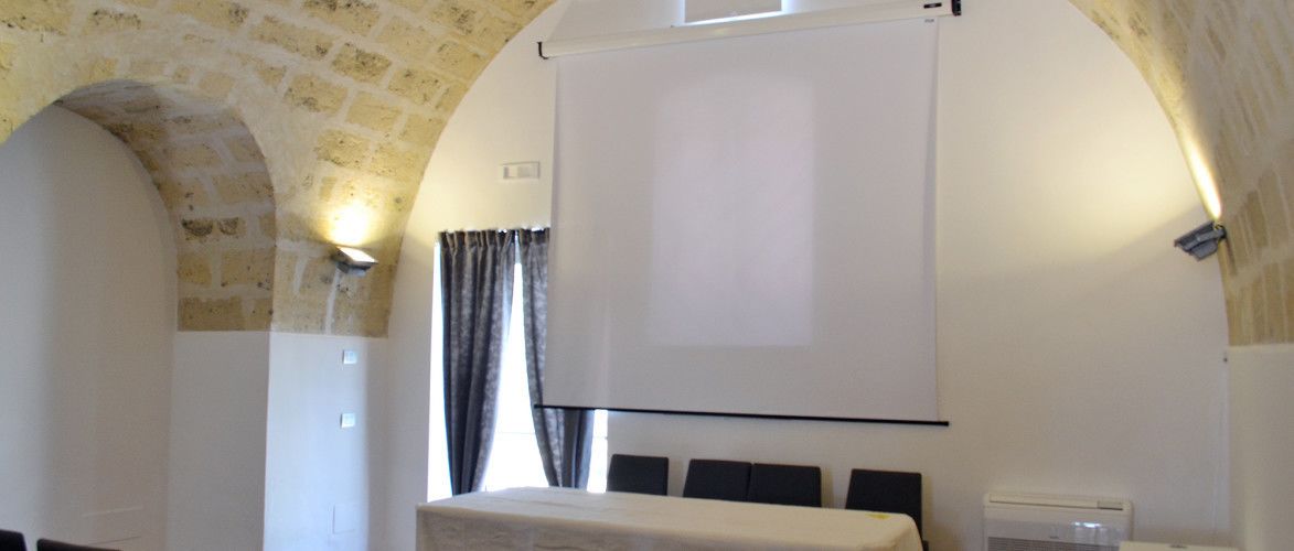 A room with a bed, a projector screen, and stone walls.