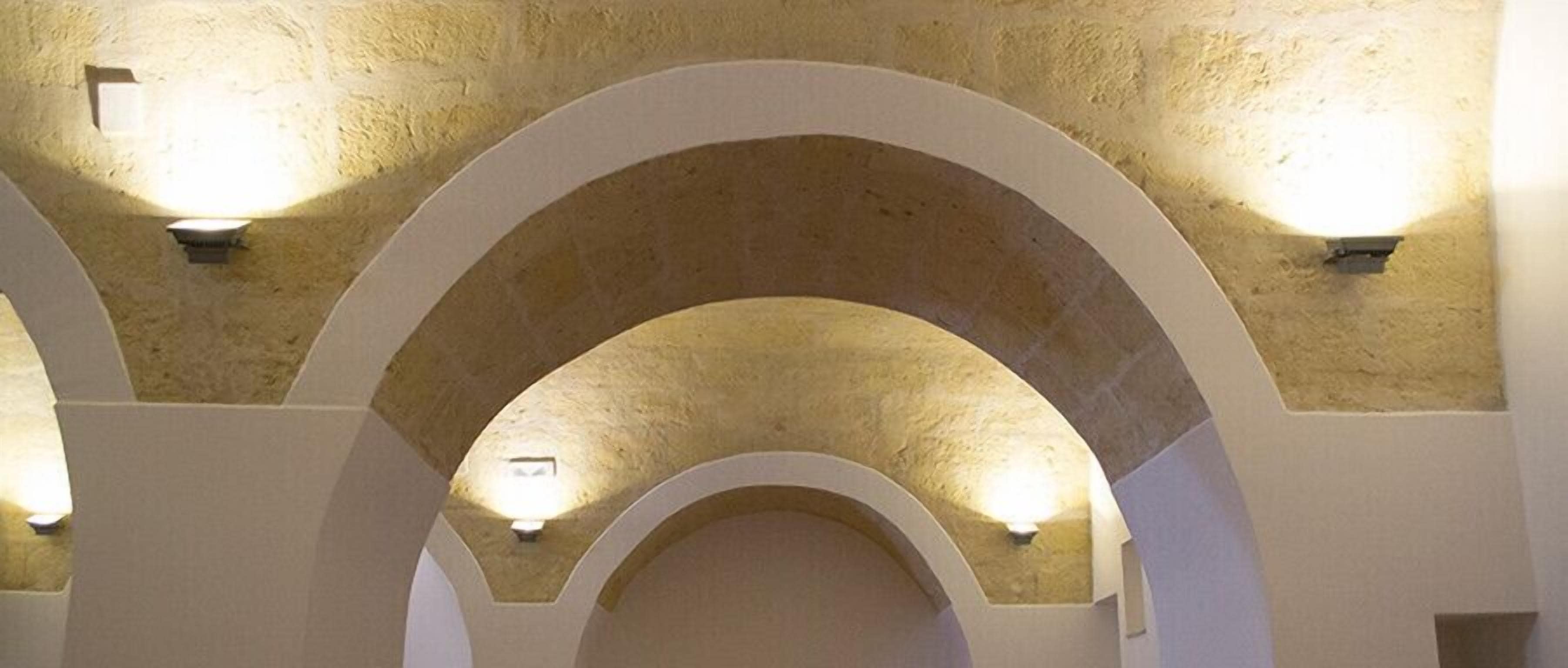 A series of arched passageways with light fixtures on the walls.