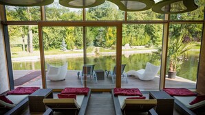 Una habitación iluminada por el sol, con sillones de mimbre y vistas a un lago.