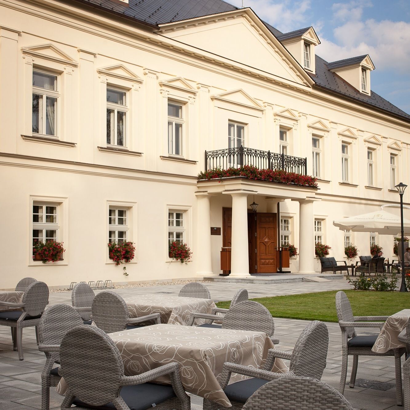 A large building with a white facade, multiple windows, and a balcony with a wrought iron railing.