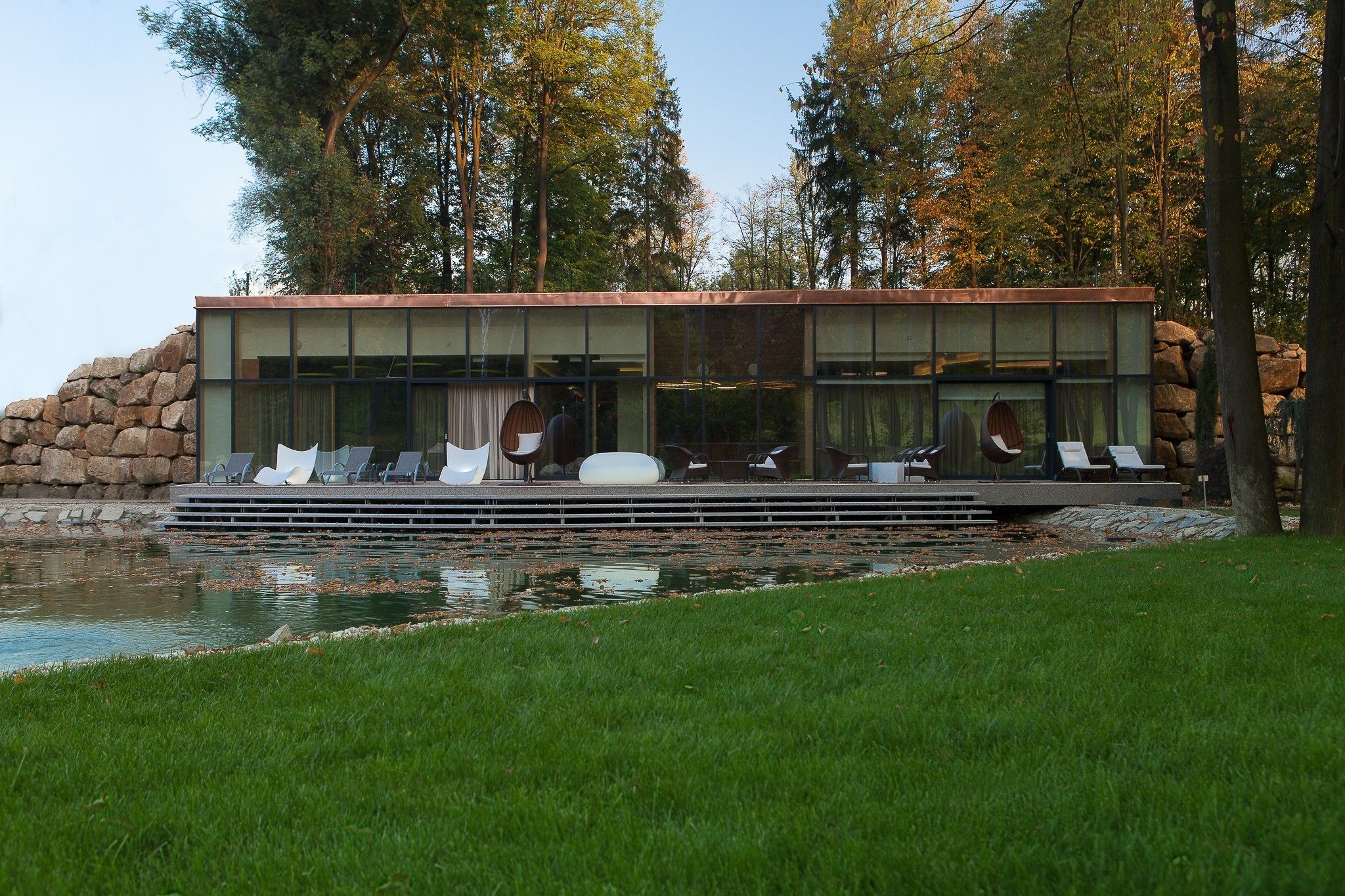 A modern building with a pool and lounge chairs.
