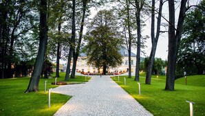 Un sendero empedrado que conduce a un edificio con un gran árbol en el centro.