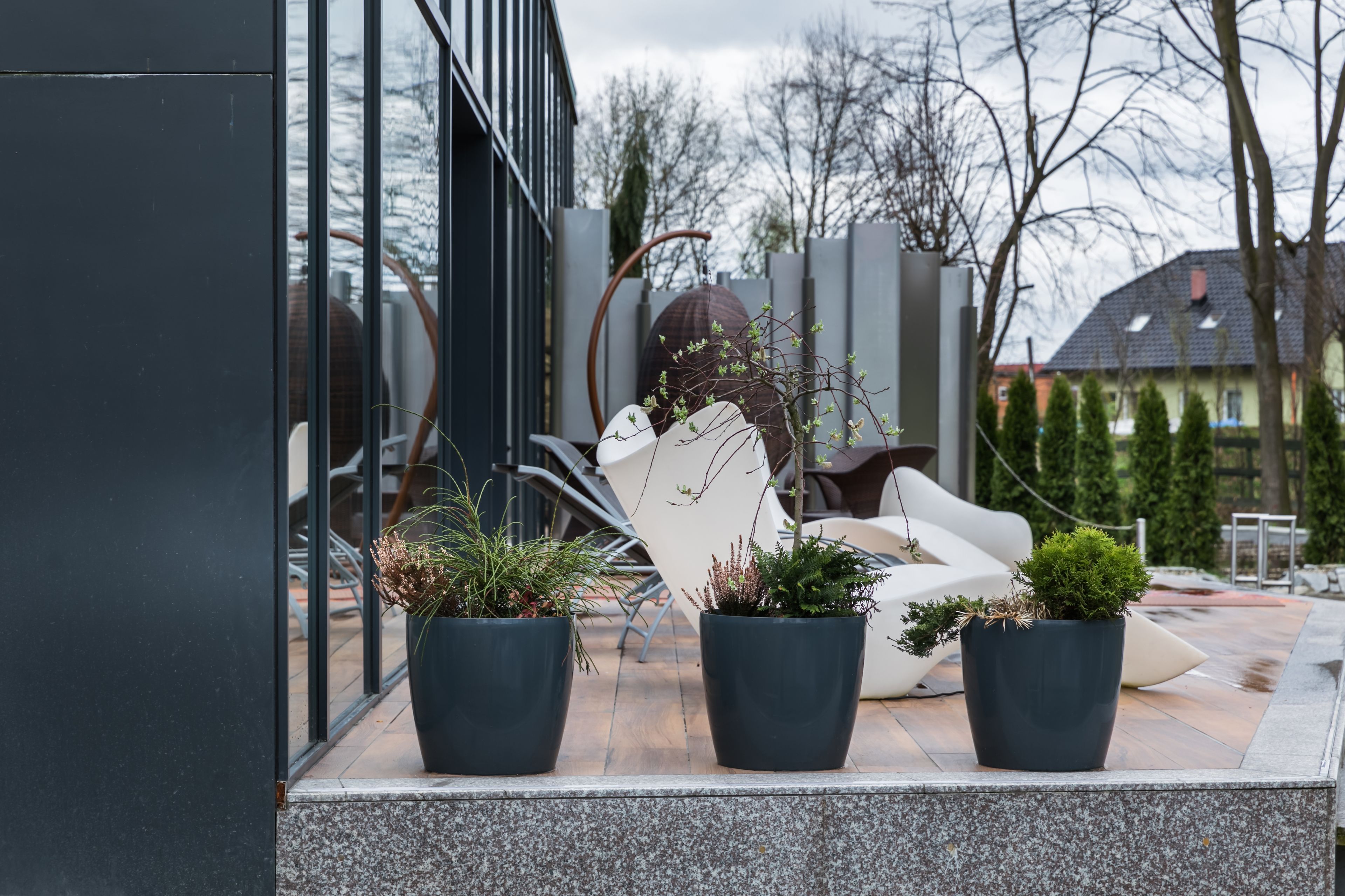 A modern outdoor seating area with potted plants and a white chair.