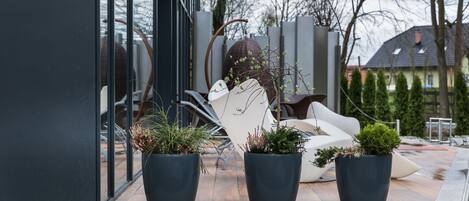 A modern outdoor seating area with potted plants and a white chair.