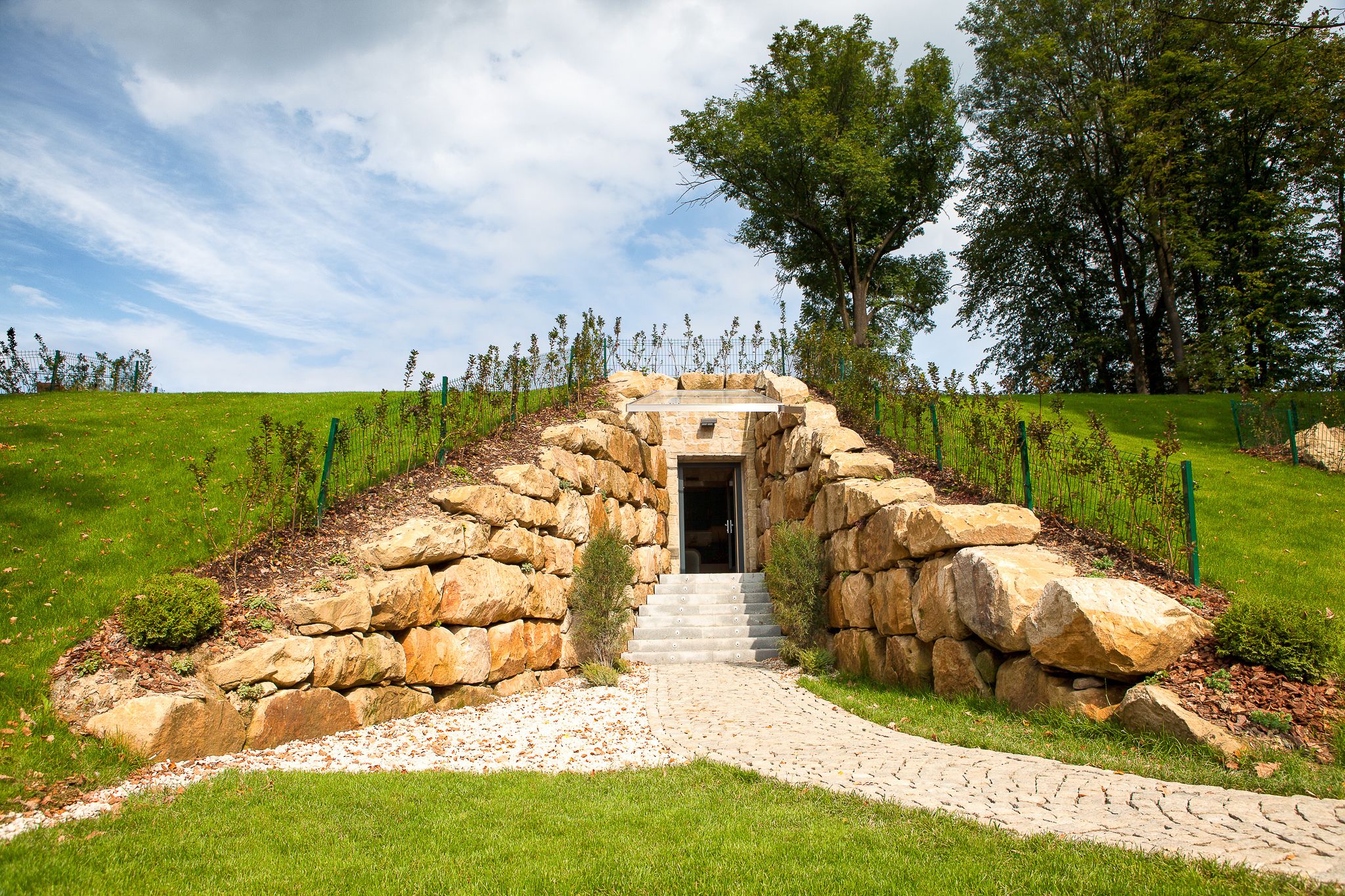 A stone staircase leading to a building entrance surrounded by a grassy area and trees.