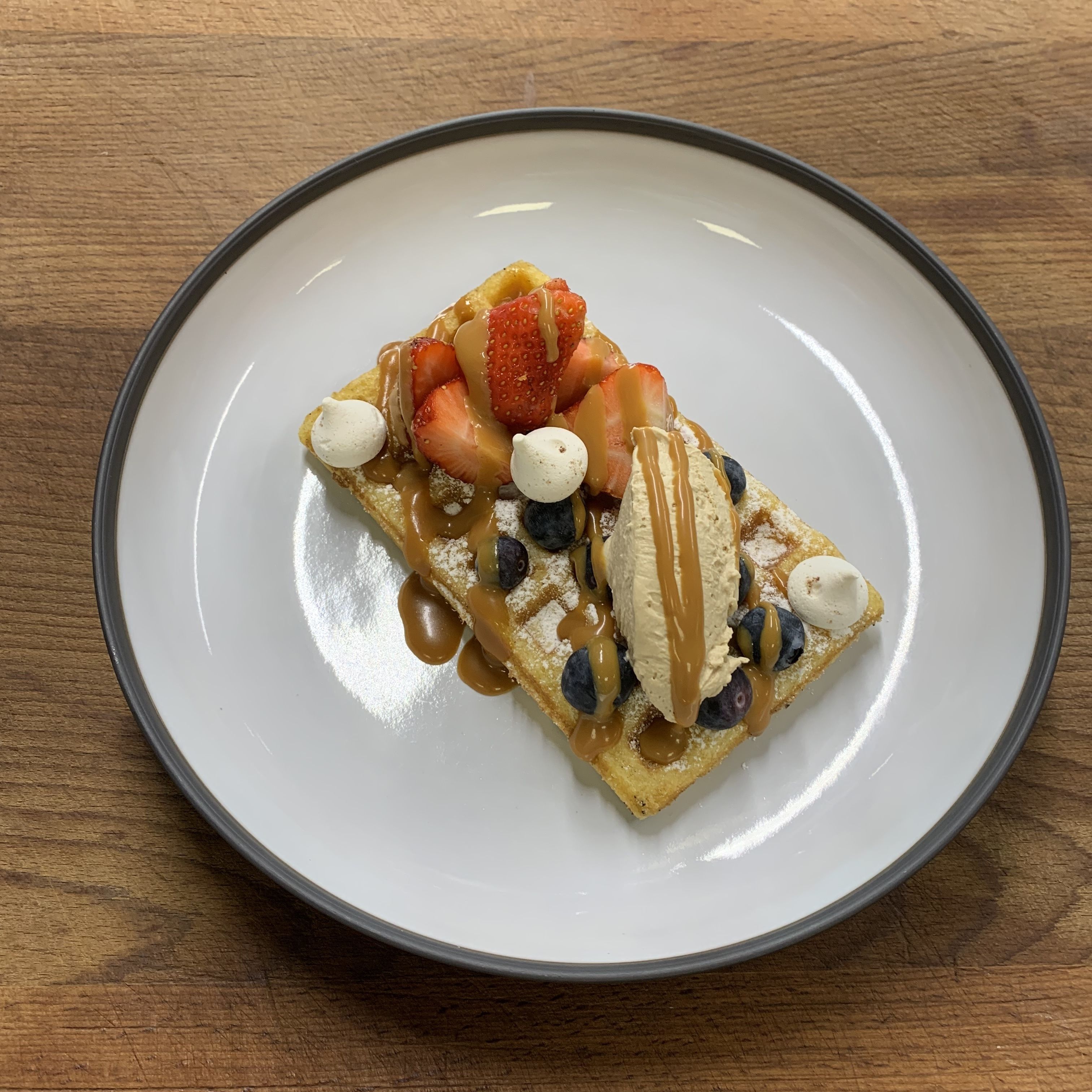 Un dessert servi sur une assiette blanche, avec une table en bois en arrière-plan.