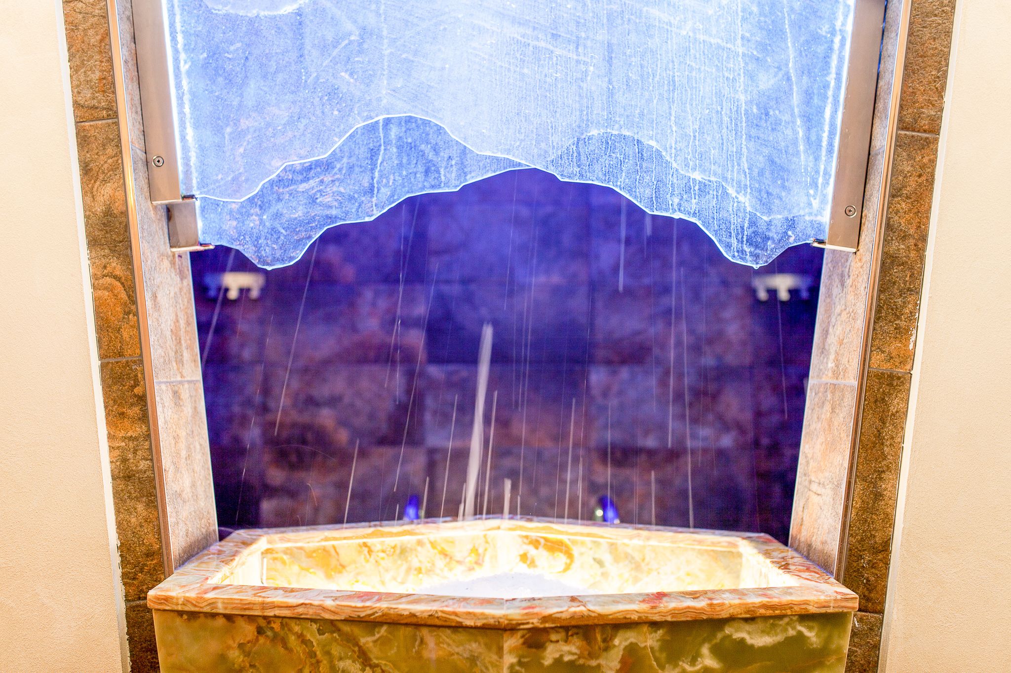 A stone fountain with water jets and a decorative glass cover.
