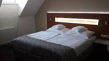 A bedroom with a bed, a bedside table, a window, and a radiator.