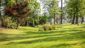 A well-maintained grassy area with trees and a building in the background.