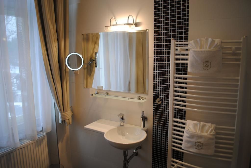 Un baño con lavamanos blanco, un espejo y un perchero para toallas.