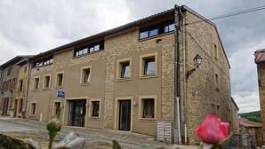 Een gebouw met twee verdiepingen, een stenen gevel, meerdere ramen en een duidelijke ingang.