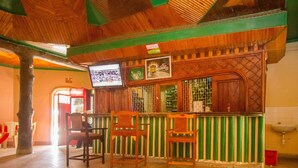 A bar area with wooden furniture, a television screen, and a green-striped counter. - Jamindas Paradise Motel (Kakamega)