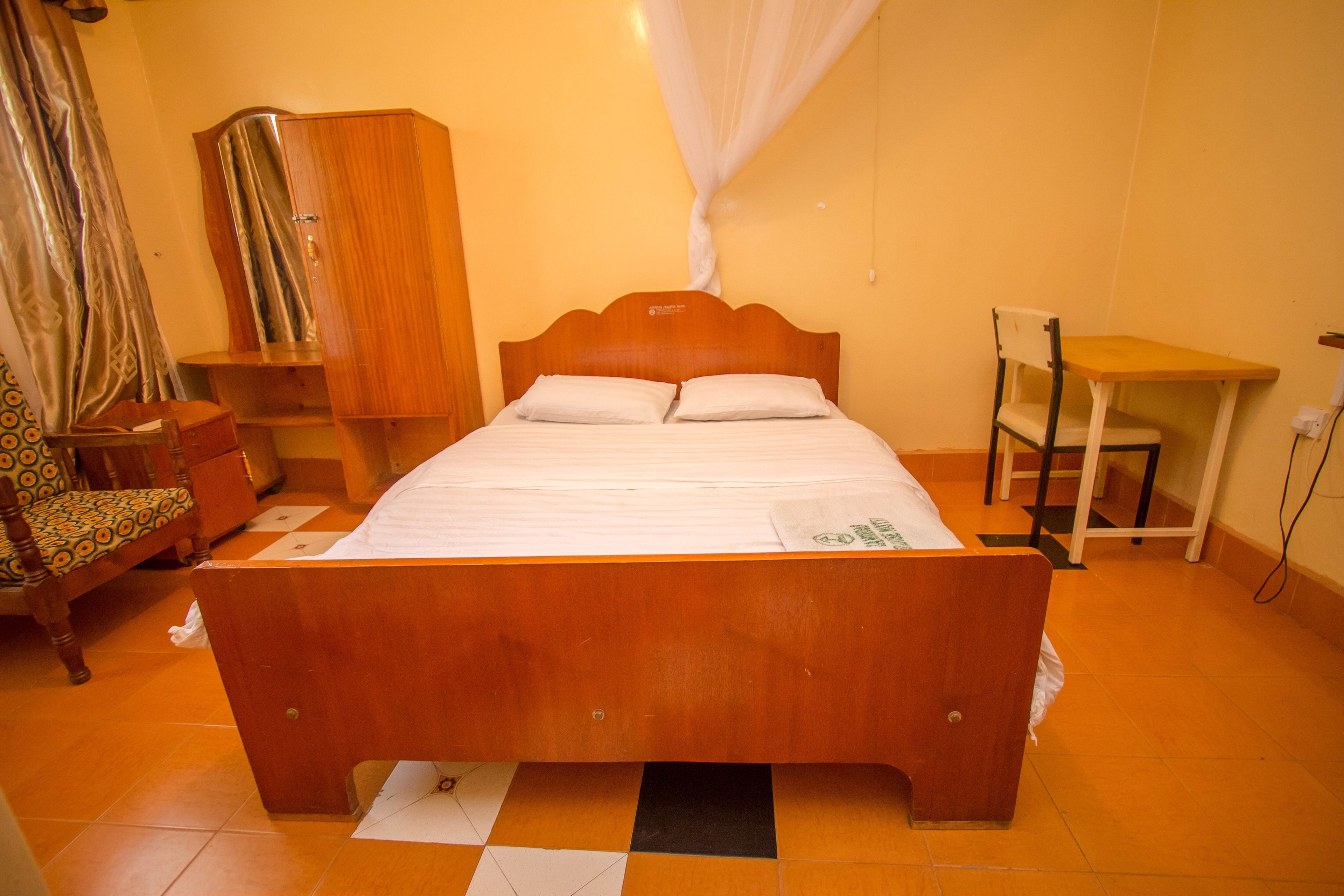 Une pièce avec un lit en bois, une armoire en bois, une petite table et une chaise.