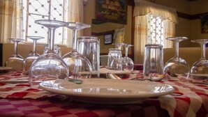 A dining table set with clear glassware and plates, with a checkered tablecloth. - Jamindas Paradise Motel (Kakamega)