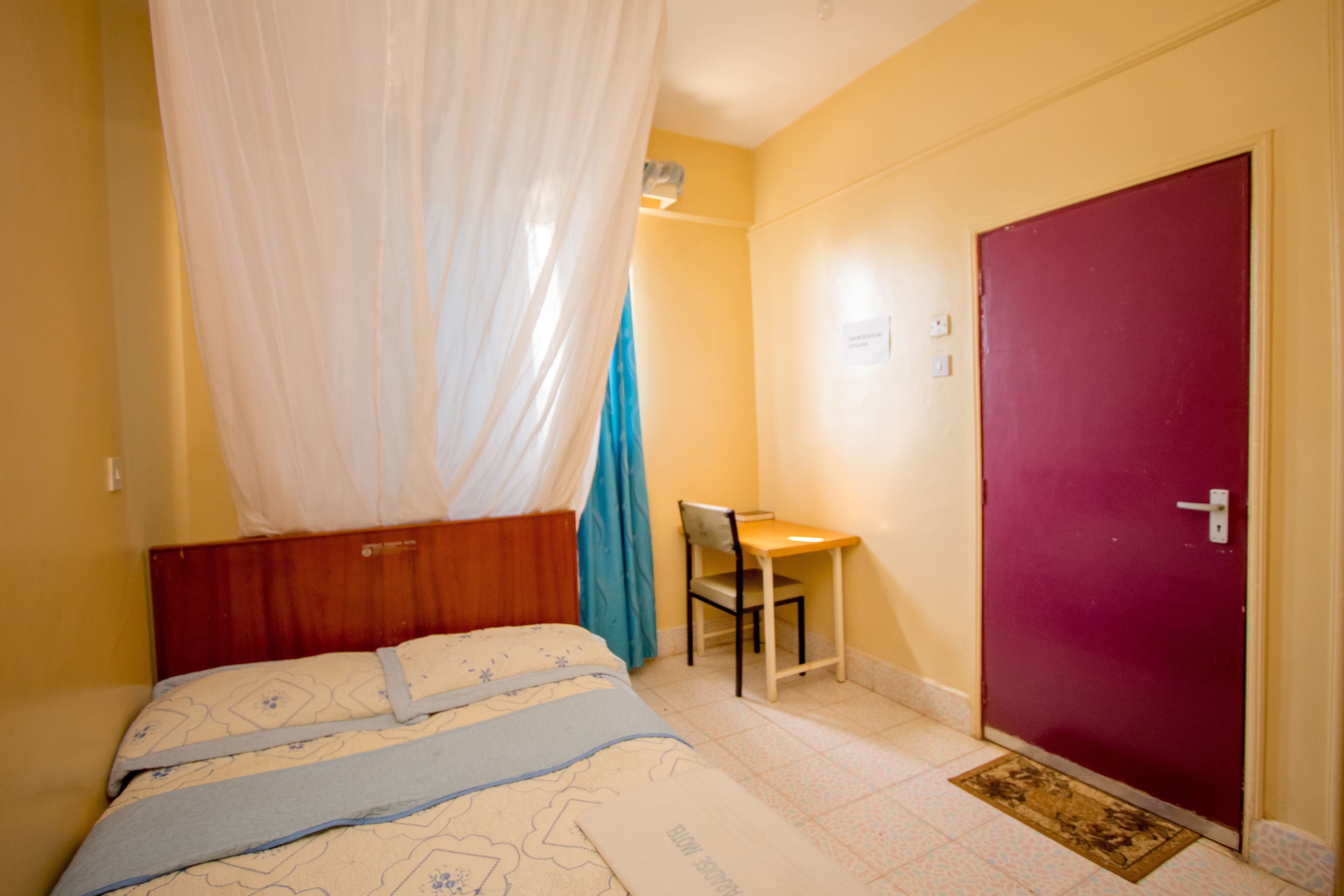 A bedroom with a bed, a desk, and a door.