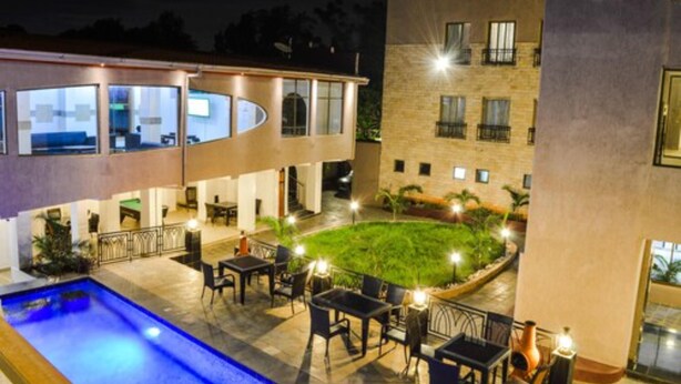 Un hotel con piscina, mobiliario exterior y un patio bien iluminado.