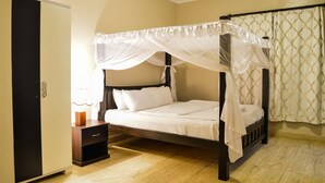 Una cama con dosel, una mesita de noche con lámpara y un armario.