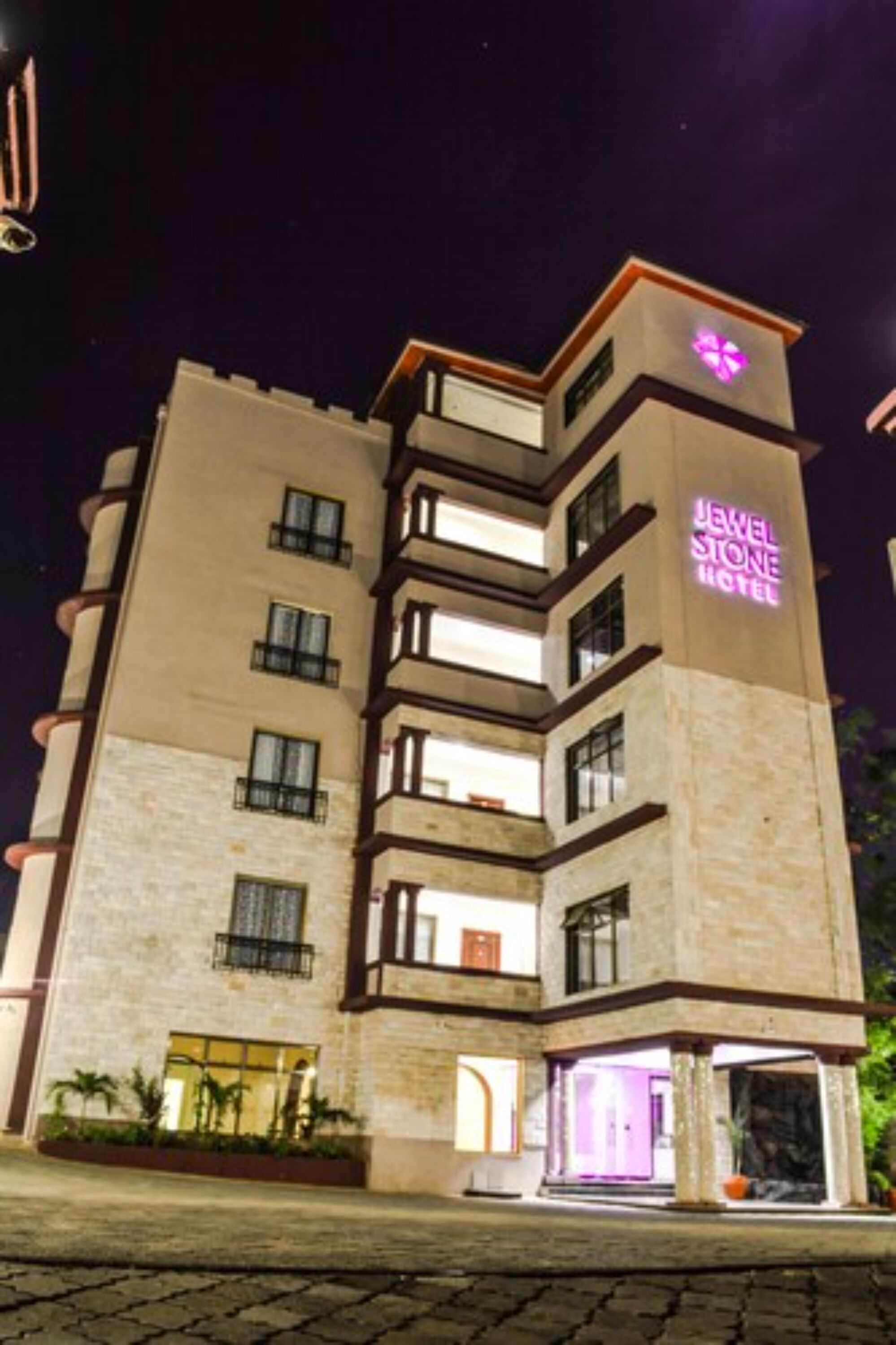 A multi-story hotel with a prominent neon sign for the "Jewel Stone Hotel."