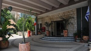 L’entrée d’un hôtel, avec une façade en pierre, des marches menant à la porte et des plantes en pot.
