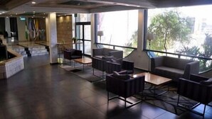 Un hall d’entrée spacieux, doté de meubles modernes, de grandes fenêtres et offrant une vue sur la verdure environnante.