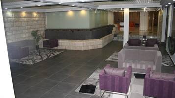 A lobby with a reception desk, seating area, and a stone wall.