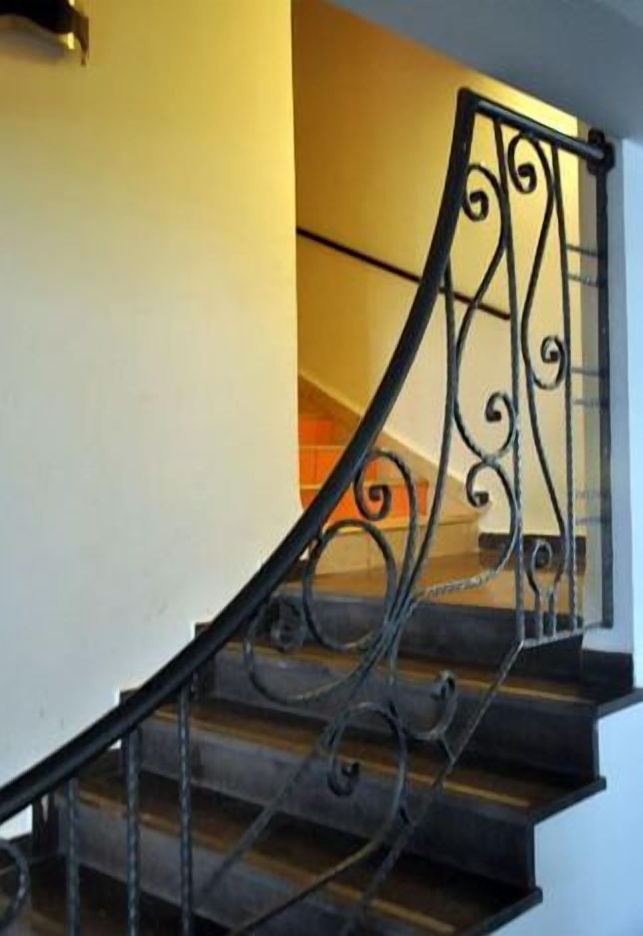 Una escalera con barandillas de metal ornamentadas y peldaños de madera.