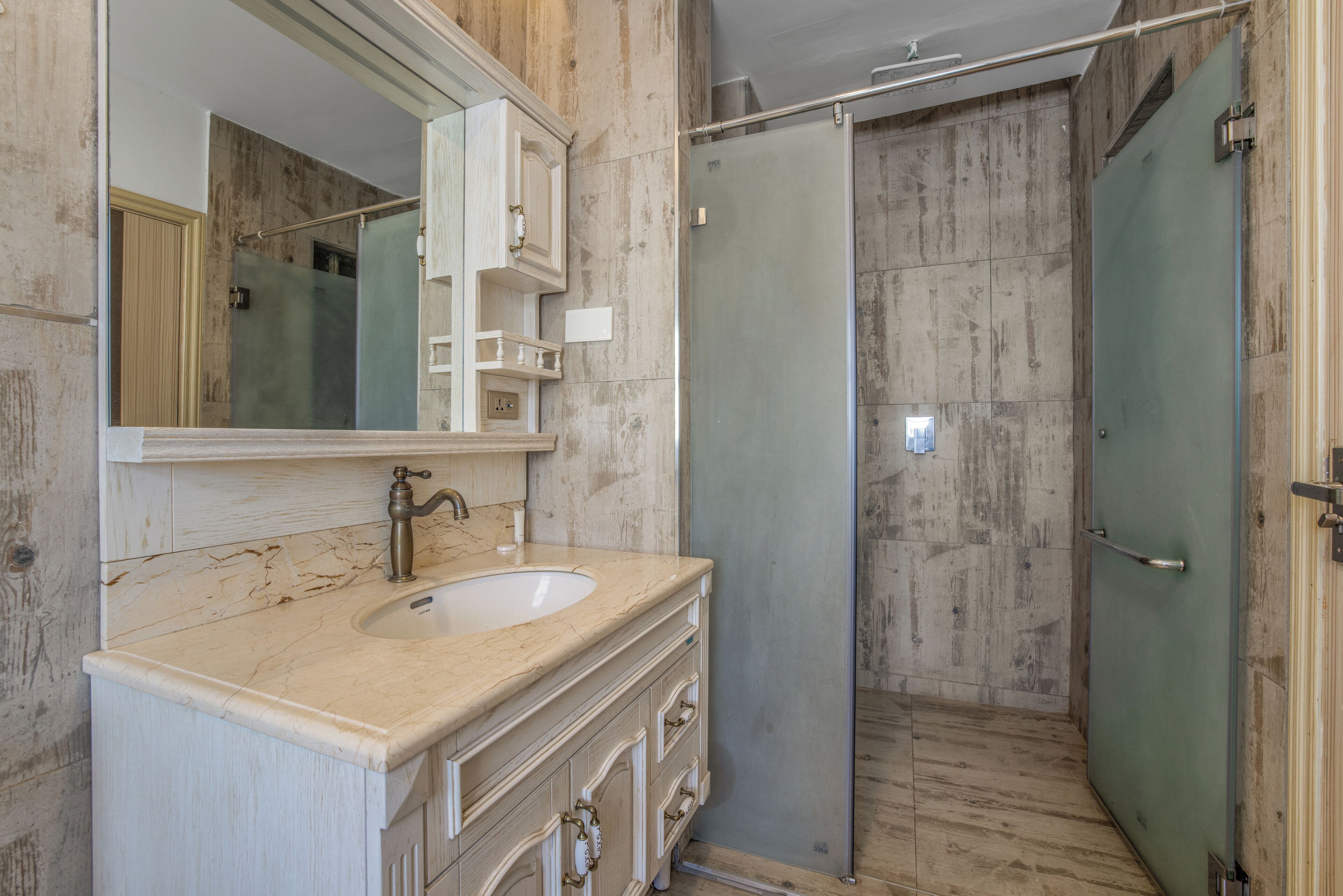 Un baño con lavamanos de mármol, un espejo grande y una cabina de ducha de vidrio.