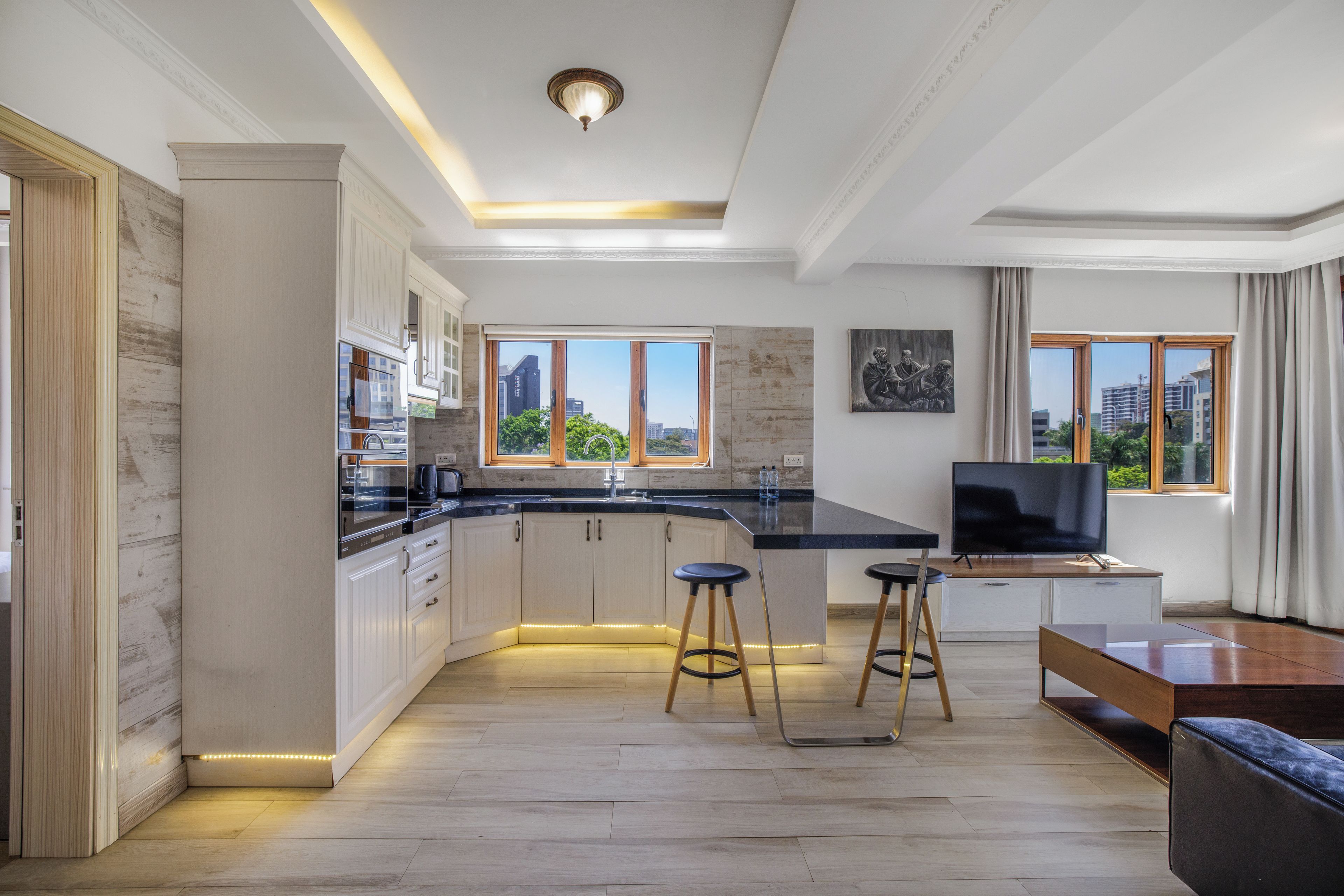 Una cocina moderna con una isla grande, taburetes de bar y un televisor de pantalla plana.
