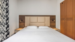 Un dormitorio ordenado con una cama grande, cabecera de madera, lámparas de noche y un armario.
