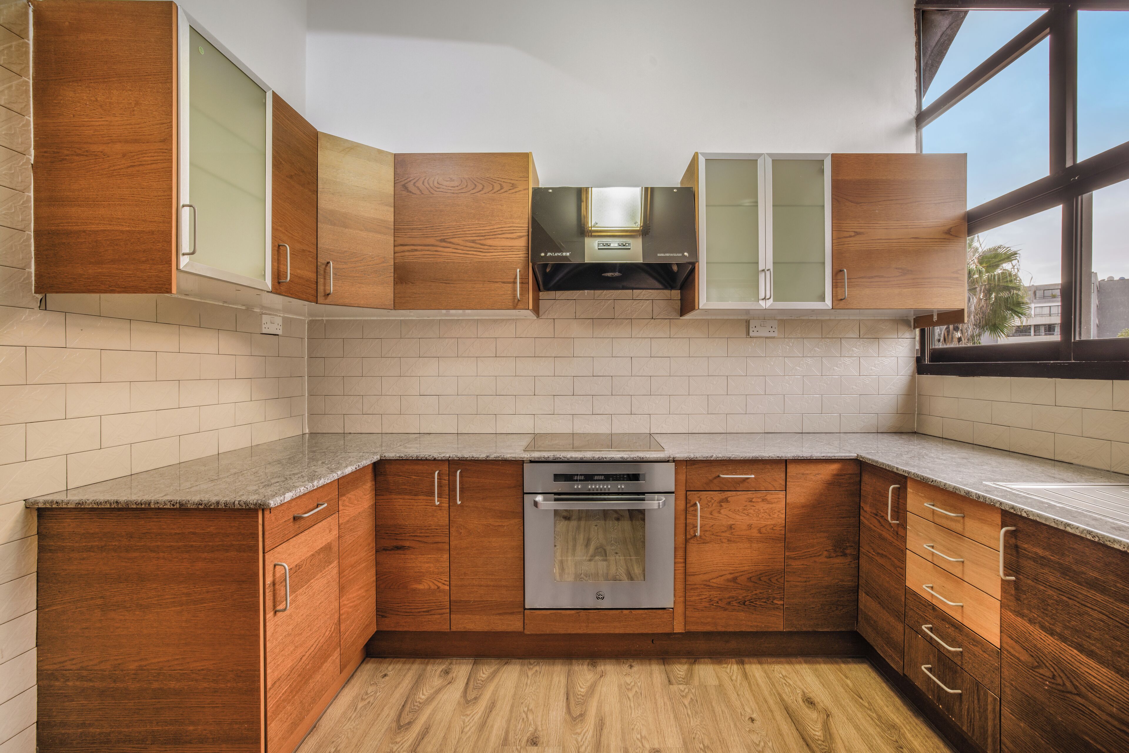 Una cucina con mobili in legno, un forno in acciaio inox e una finestra che permette l'illuminazione naturale.
