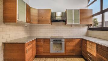 Una cucina con mobili in legno, un forno in acciaio inox e una finestra che permette l'illuminazione naturale.