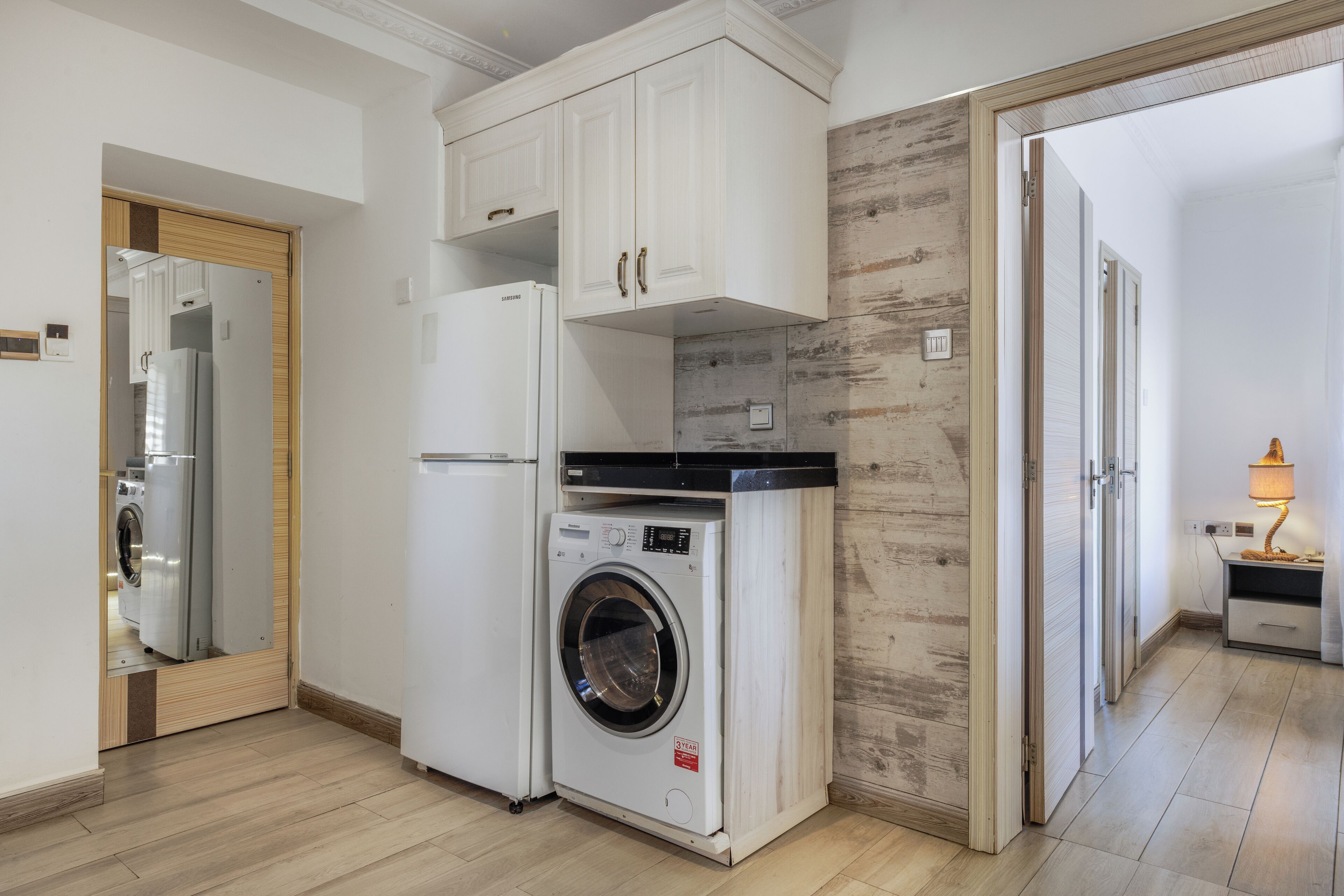 Una cocina compacta con lavadora, refrigerador y armarios de madera.