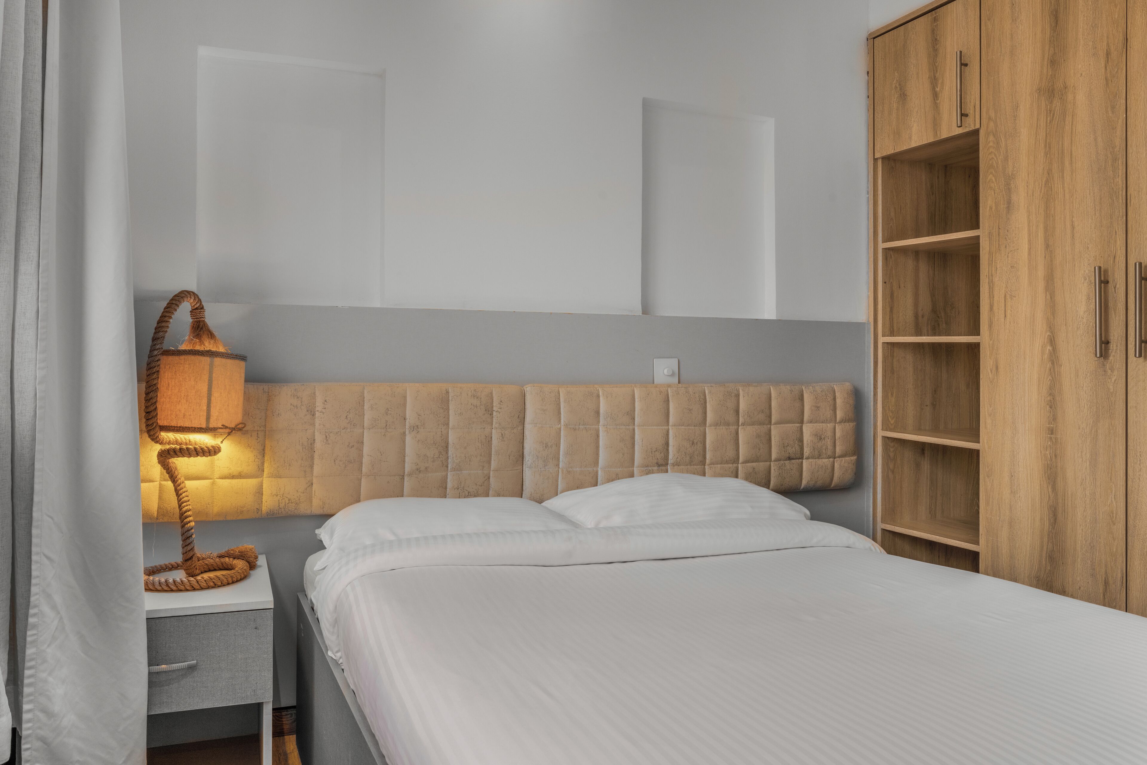 Ein Schlafzimmer mit einem Bett, einem Nachttisch, einer Lampe und einem Holzschrank.