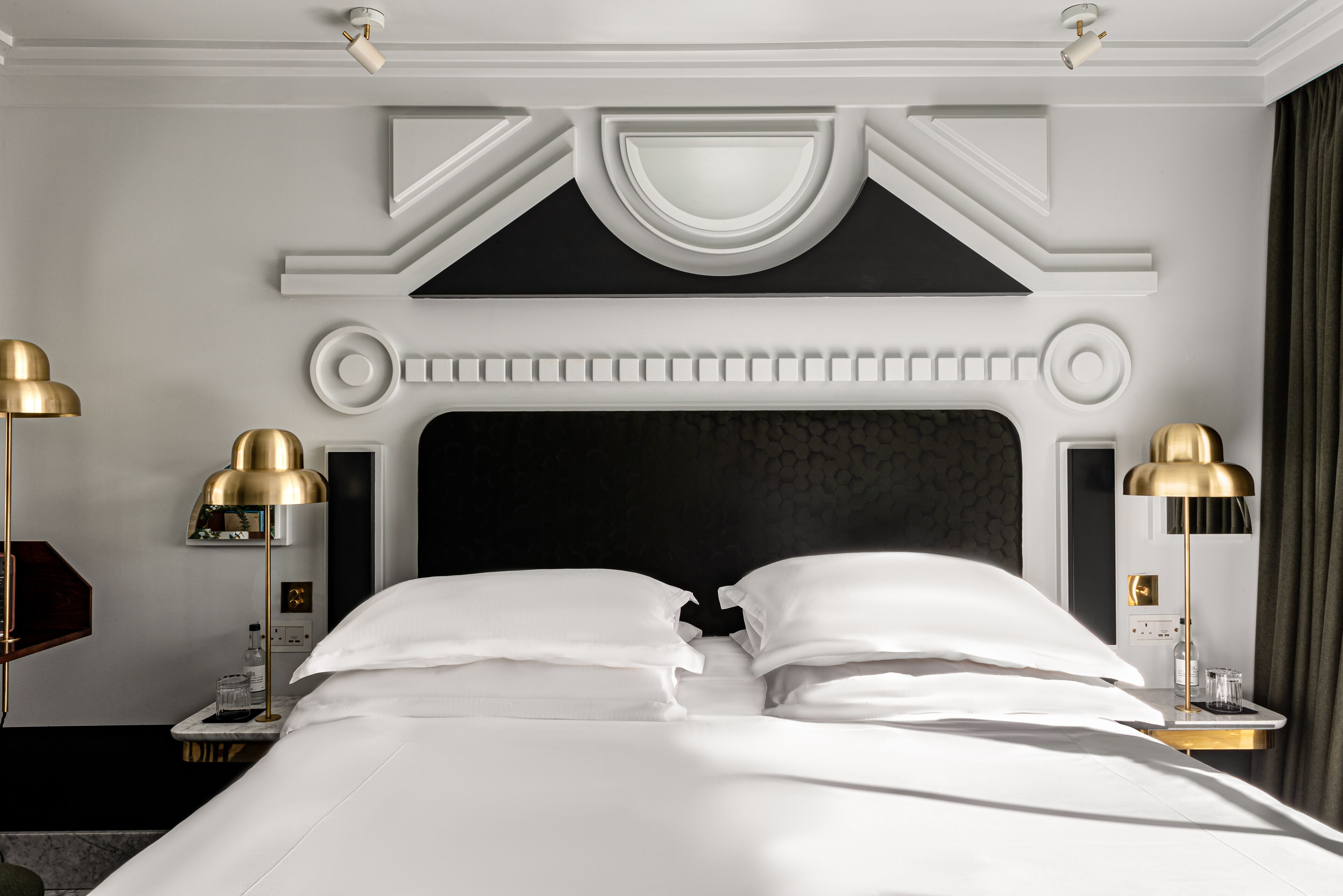 A hotel room with a large bed, two bedside tables, and two lamps.