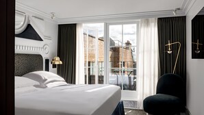 Una habitación de hotel moderna con una cama grande, vistas a la ciudad y un balcón.