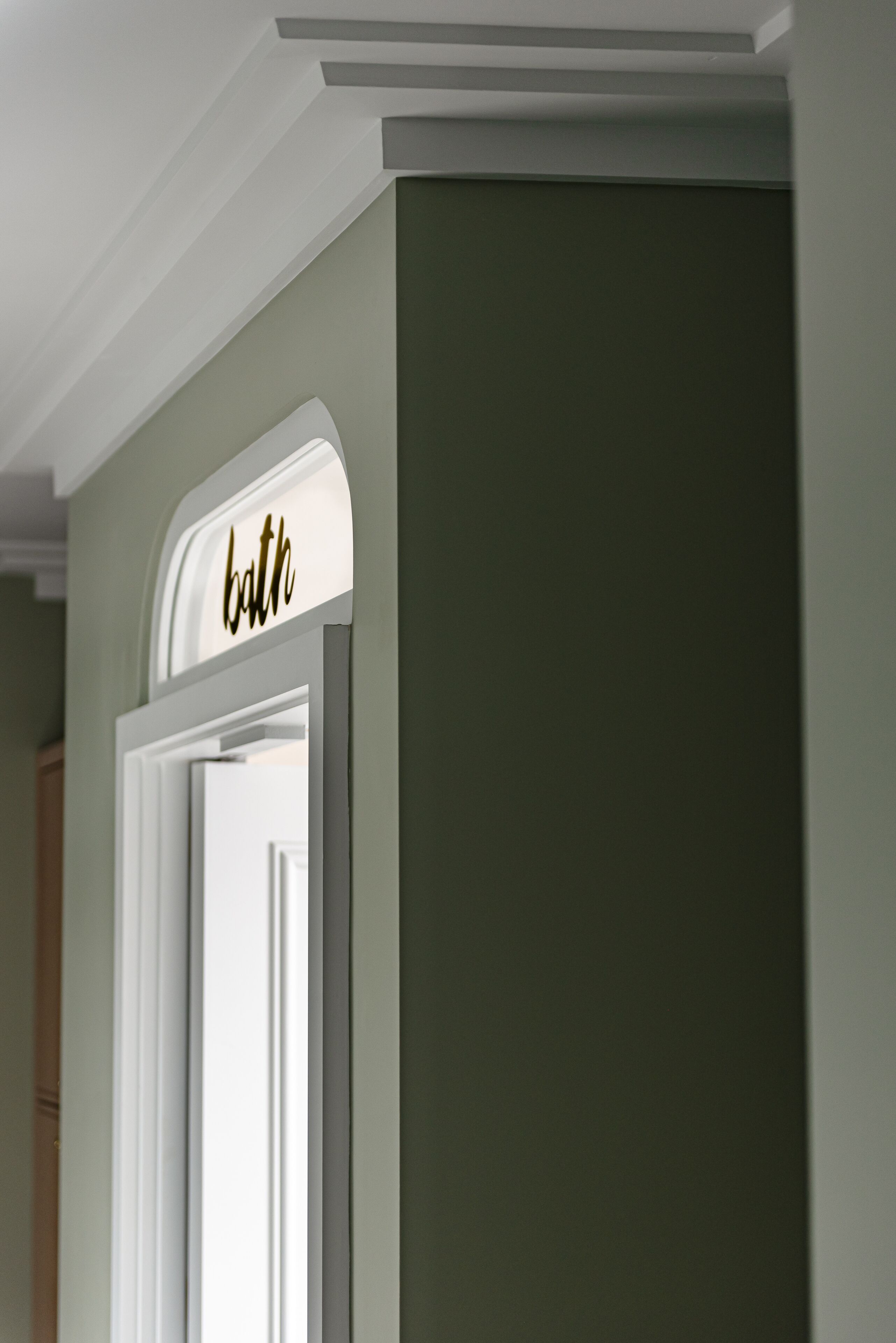 A bathroom door with a sign that reads "bath" in gold lettering.