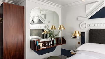 Ein modernes Hotelzimmer mit einem großen Bett, einem Schminktisch mit Spiegel und einem Schreibtisch mit Lampe.