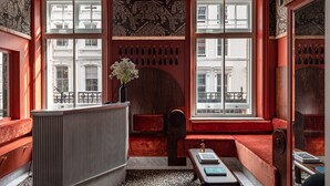 Una habitación con un banco rojo, un escritorio de madera y un techo estampado.