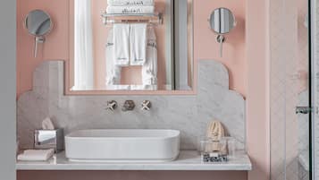 A modern bathroom with a large mirror, white sink, and black and white patterned floor tiles.