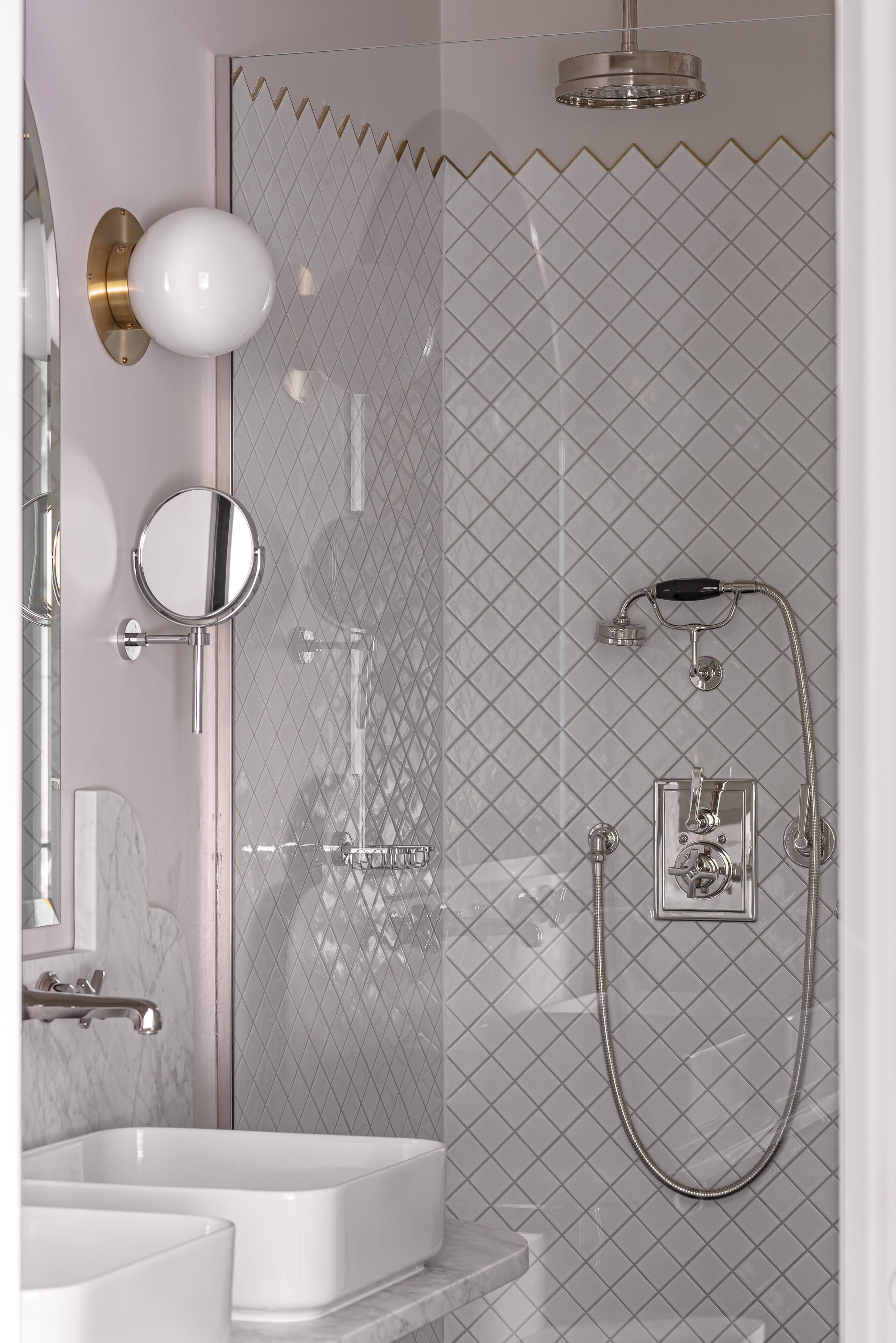 Un baño moderno con cabina de ducha de vidrio, inodoro de pared y lavamanos doble con encimera de mármol.