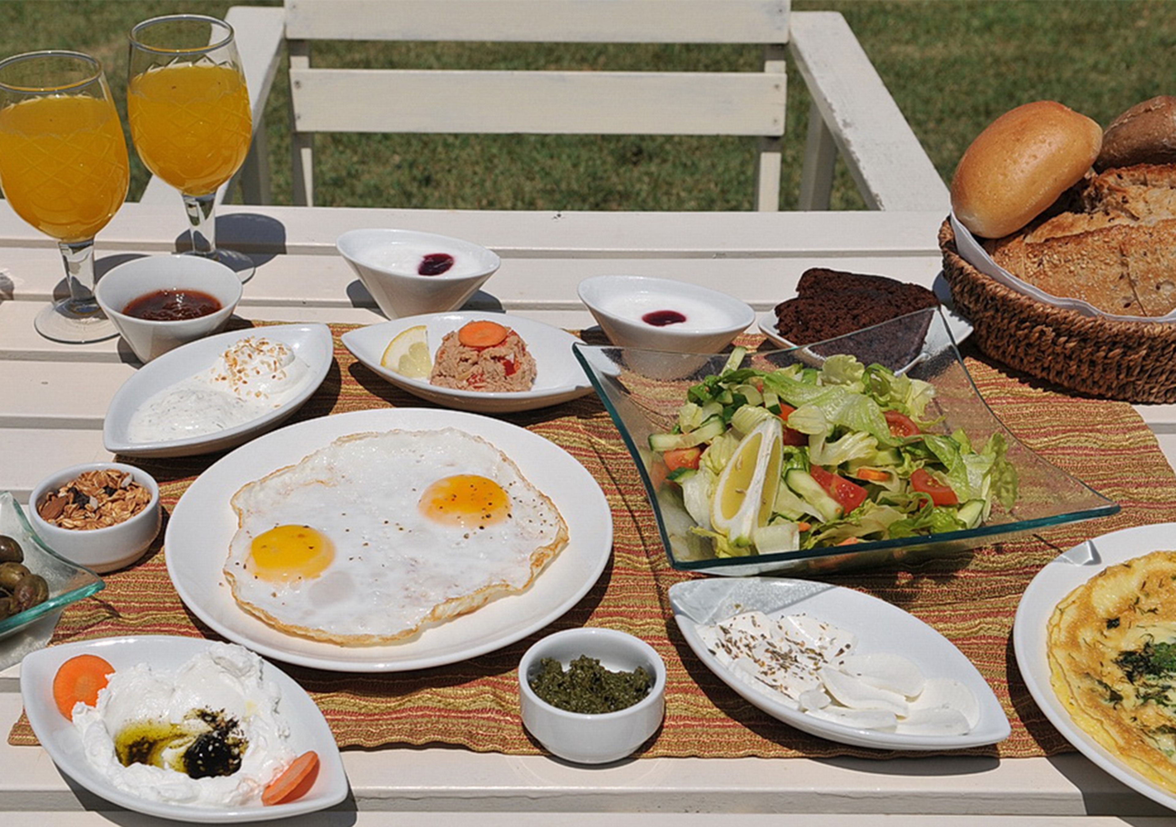 Una mesa dispuesta con diferentes alimentos para el desayuno, como huevos, pan y una ensalada.