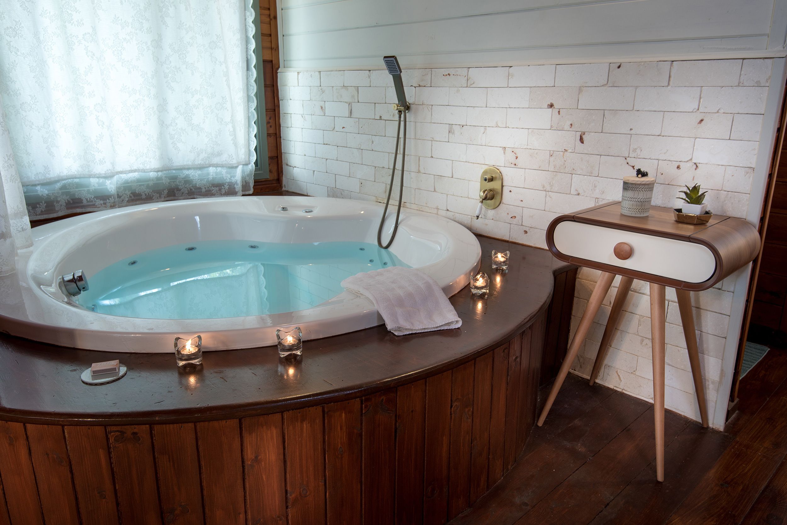 A bathroom with a wooden vanity, a white bathtub, and a small potted plant on the vanity.