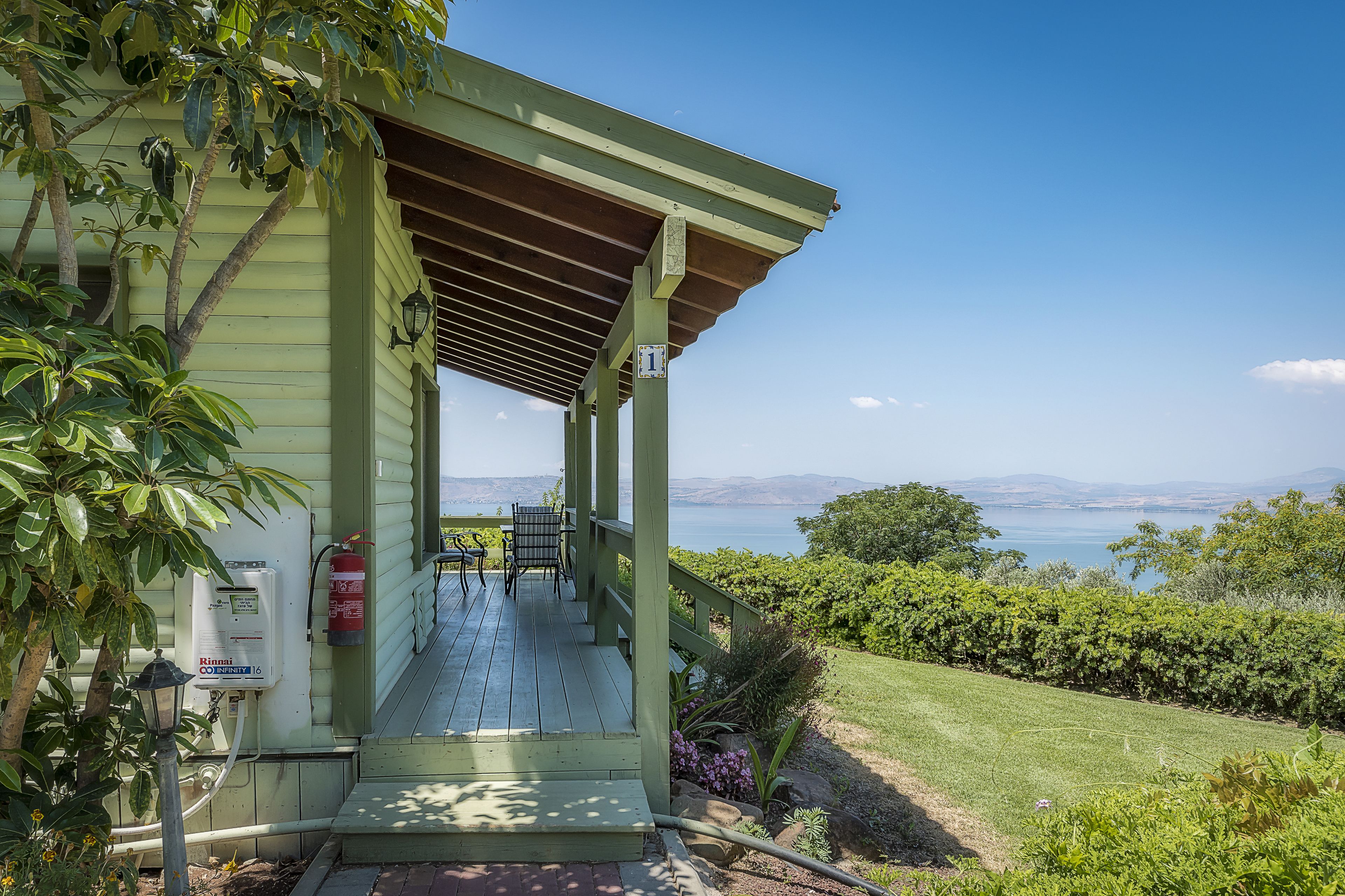 A covered porch with a view of the ocean, a fire extinguisher, and a water heater on the wall.